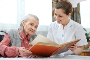 caregiver and elderly woman reading a book