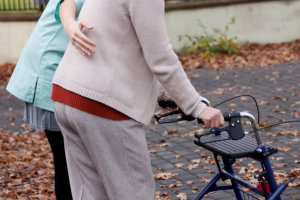 caregiver assisting elder in using walker